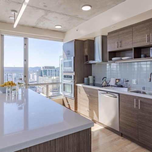 Luxury Three-Bedroom apartments in San Francisco, CA - Etta Apartments - Kitchen with Stainless Steel Appliances, a Large Island, and Modern Brown Cabinetry